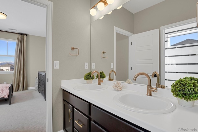 full bathroom featuring a healthy amount of sunlight, double vanity, and a sink