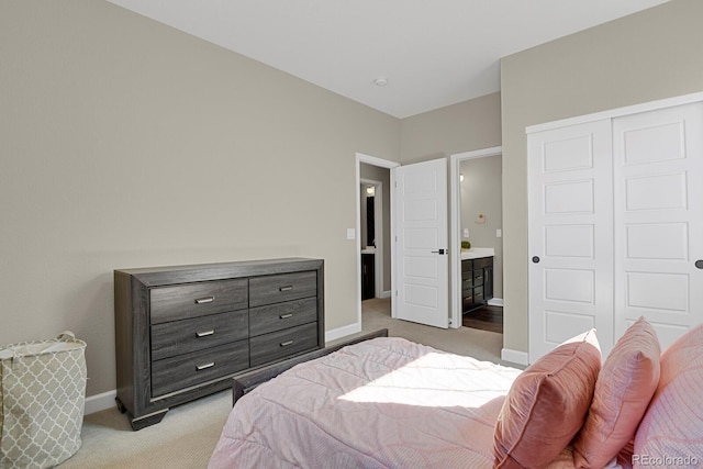 bedroom featuring light carpet, a closet, ensuite bath, and baseboards