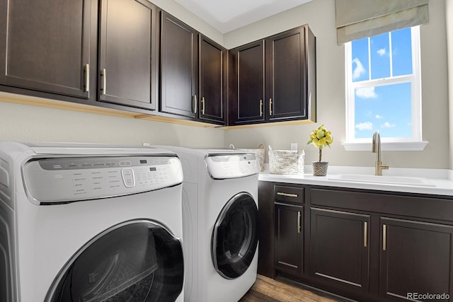 washroom with wood finished floors, a sink, cabinet space, and washer and dryer