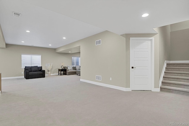 unfurnished room with carpet, visible vents, and stairway