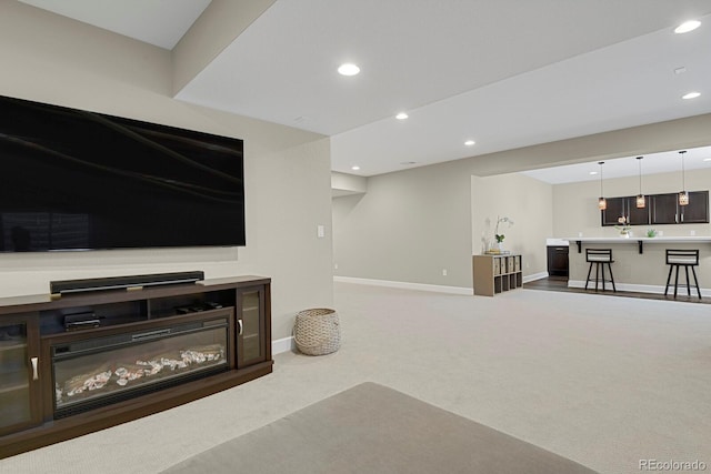 living room featuring carpet, baseboards, a glass covered fireplace, and recessed lighting