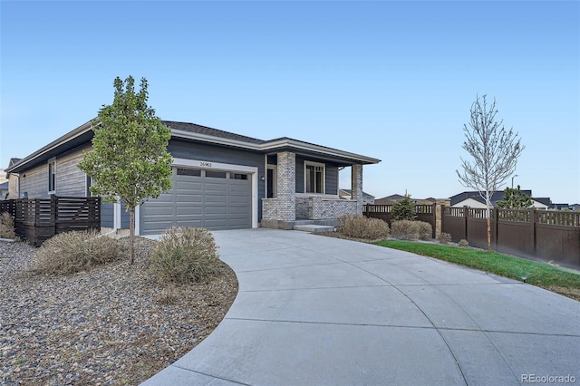 prairie-style home with concrete driveway, fence, a porch, and a garage