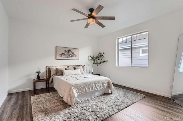 bedroom with baseboards, multiple windows, and wood finished floors