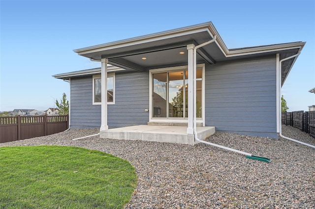 rear view of house featuring a patio, a lawn, and fence