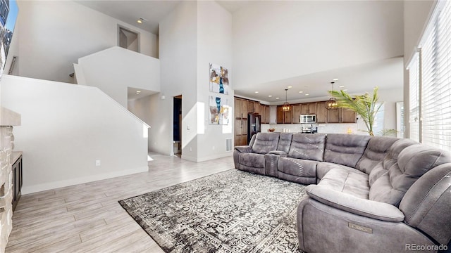 living room with visible vents, a fireplace, light wood-style flooring, and a high ceiling