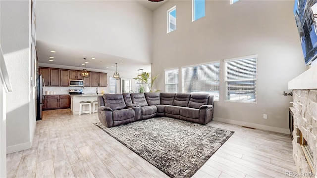 living room featuring plenty of natural light, light wood-type flooring, a fireplace, and baseboards