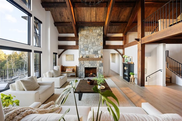 534 W Meadow Rd, Evergreen, CO 80439 - living area featuring a wooden ceiling with exposed beams, high vaulted ceiling, light wood finished floors, a stone fireplace, and stairs