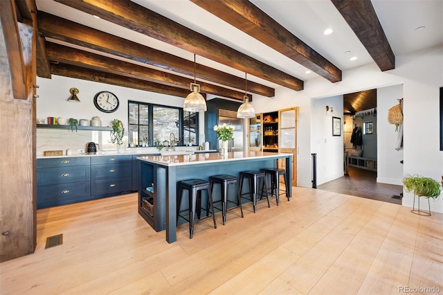 534 W Meadow Rd, Evergreen, CO 80439 - kitchen featuring blue cabinets, open shelves, light countertops, a kitchen breakfast bar, and light wood finished floors