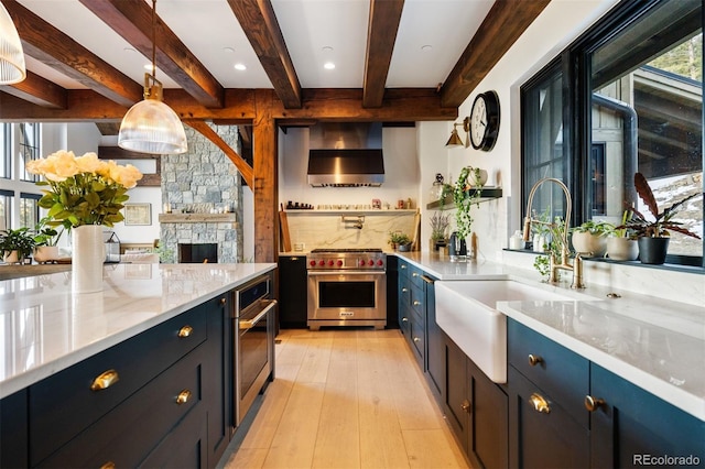 534 W Meadow Rd, Evergreen, CO 80439 - kitchen featuring appliances with stainless steel finishes, wall chimney range hood, beamed ceiling, light stone countertops, and hanging light fixtures