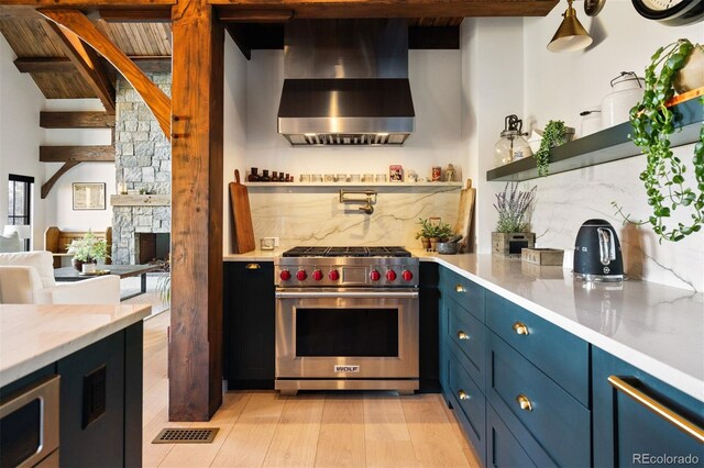 534 W Meadow Rd, Evergreen, CO 80439 - kitchen featuring wall chimney exhaust hood, stainless steel appliances, blue cabinetry, and tasteful backsplash