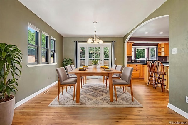 215 Sunland St, Louisville, CO 80027 - dining space with a chandelier, arched walkways, healthy amount of natural light, and light wood-style floors