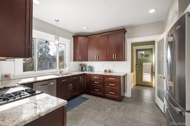 kitchen with sink, hanging light fixtures, tasteful backsplash, light stone counters, and stainless steel appliances