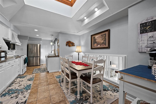 dining area with sink, a tray ceiling, and light tile patterned flooring