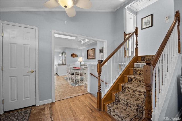 stairway with crown molding, wood-type flooring, and ceiling fan