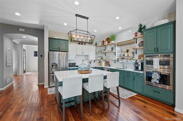 kitchen with a kitchen island, appliances with stainless steel finishes, dark hardwood / wood-style floors, a notable chandelier, and sink