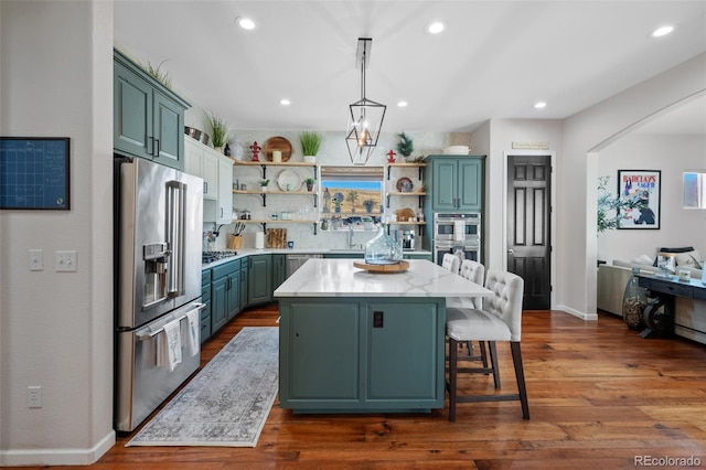 kitchen featuring a kitchen island, backsplash, dark hardwood / wood-style flooring, stainless steel appliances, and decorative light fixtures