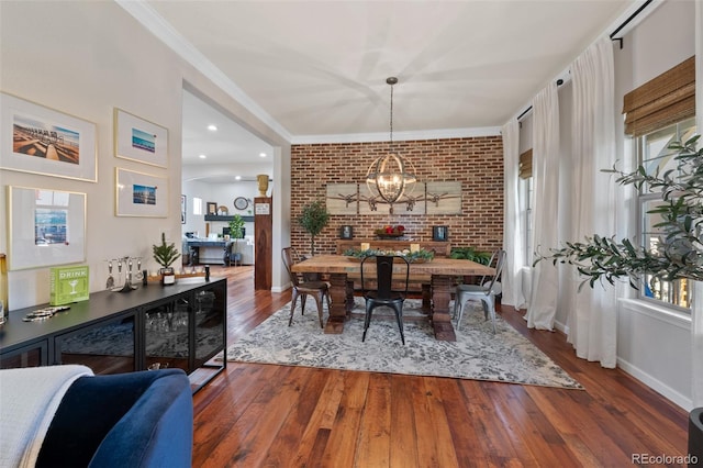 dining room featuring a notable chandelier, ornamental molding, hardwood / wood-style flooring, and brick wall