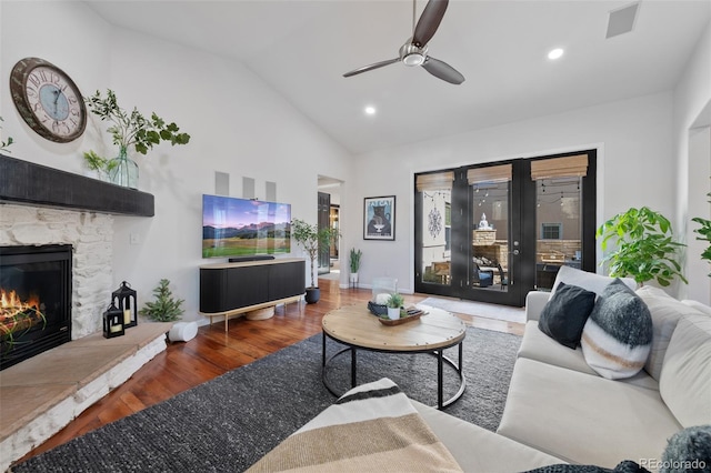 living room featuring ceiling fan, a fireplace, vaulted ceiling, and dark hardwood / wood-style floors