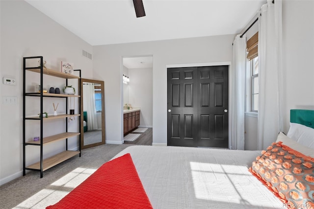 carpeted bedroom featuring a closet, ensuite bath, and ceiling fan