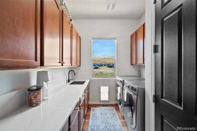 washroom featuring independent washer and dryer, hardwood / wood-style flooring, cabinets, and sink