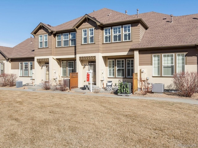 view of front of property featuring cooling unit, roof with shingles, and a front lawn