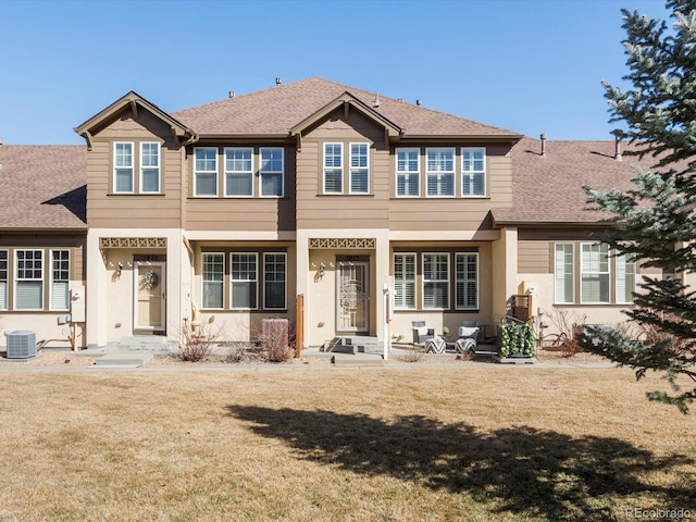 view of front of home with central air condition unit, a front lawn, and a shingled roof