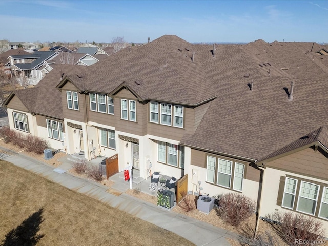 view of property featuring cooling unit, a residential view, roof with shingles, and a patio area