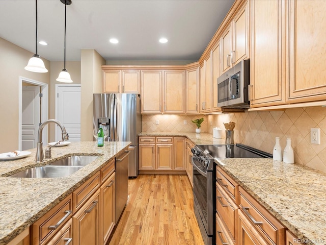 kitchen with light wood finished floors, tasteful backsplash, pendant lighting, stainless steel appliances, and a sink