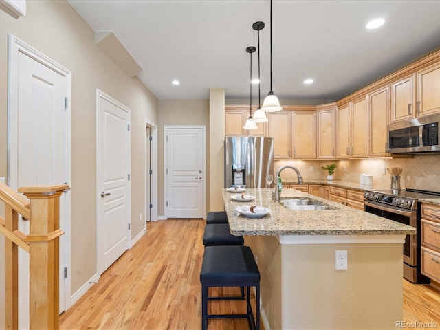 kitchen featuring a sink, light wood-style floors, tasteful backsplash, and appliances with stainless steel finishes