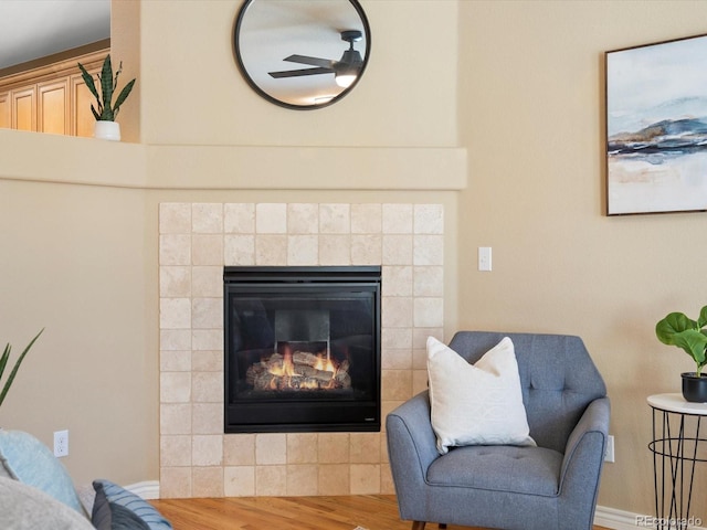 interior space with wood finished floors, a fireplace, baseboards, and ceiling fan