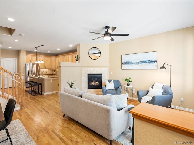 living room with light wood finished floors, recessed lighting, a fireplace, and baseboards