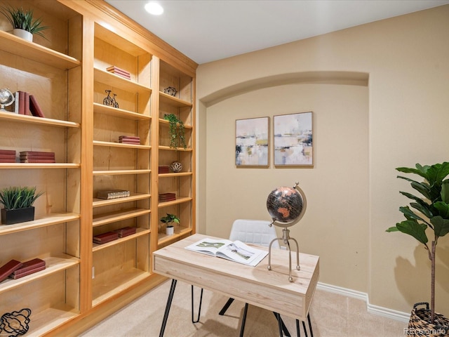 office area featuring baseboards, arched walkways, and light carpet