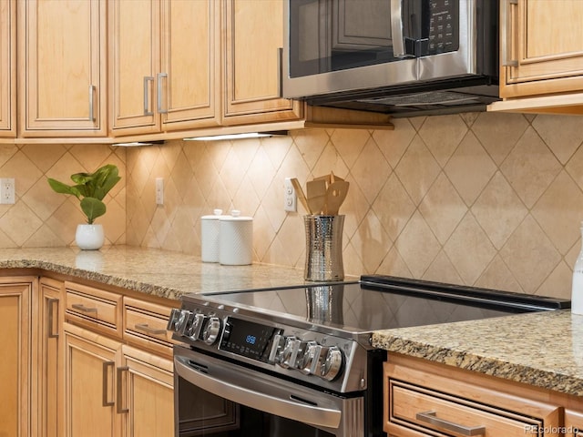 kitchen featuring light stone counters, backsplash, and appliances with stainless steel finishes