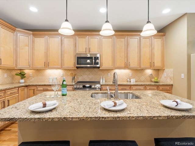 kitchen with a sink, decorative light fixtures, a kitchen breakfast bar, appliances with stainless steel finishes, and decorative backsplash