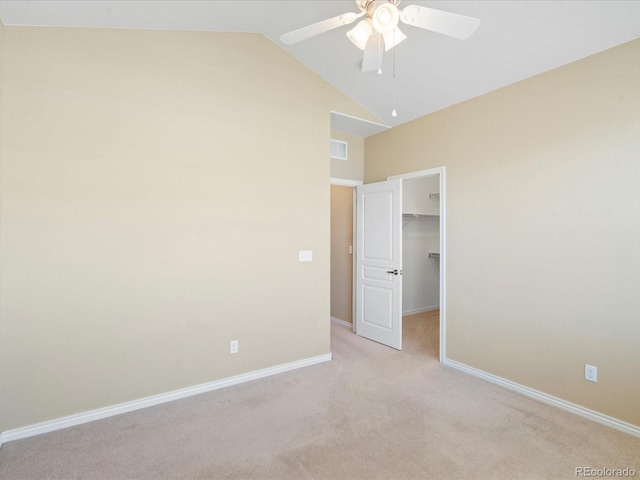 unfurnished bedroom featuring a spacious closet, visible vents, baseboards, vaulted ceiling, and light carpet