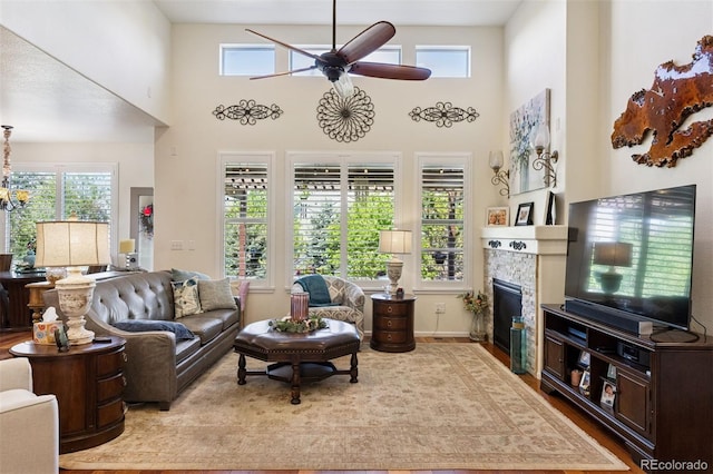 12189 Windy Trail Ln, Parker, CO 80138 - living area featuring a ceiling fan, healthy amount of natural light, a glass covered fireplace, wood finished floors, and a towering ceiling