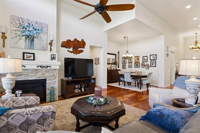 12189 Windy Trail Ln, Parker, CO 80138 - living room featuring a chandelier, wood finished floors, a towering ceiling, a ceiling fan, and a stone fireplace