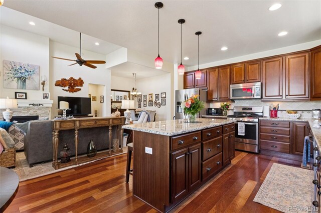 12189 Windy Trail Ln, Parker, CO 80138 - kitchen with stainless steel appliances, dark wood-style flooring, open floor plan, a ceiling fan, and decorative light fixtures