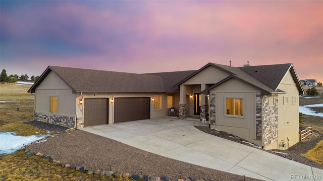 view of front of house with stucco siding, driveway, stone siding, roof with shingles, and a garage