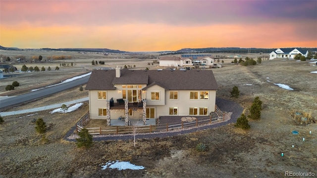 back of property at dusk featuring stucco siding, fence private yard, and a patio area