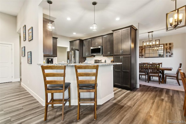 kitchen with dark brown cabinetry, dark wood-type flooring, backsplash, and stainless steel appliances