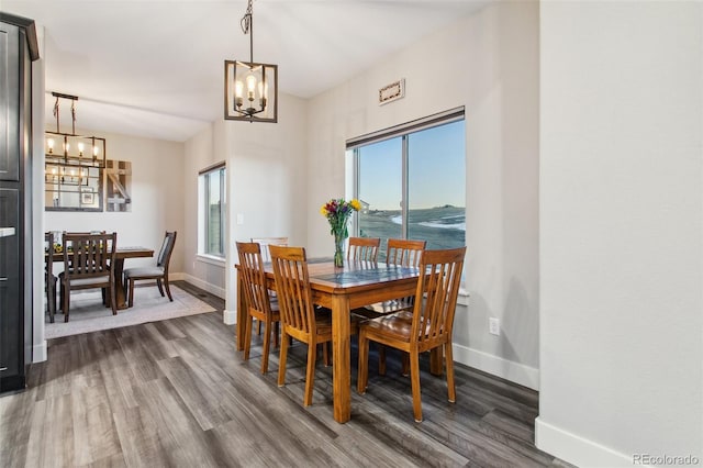 dining space with baseboards, an inviting chandelier, and dark wood finished floors