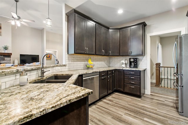 kitchen featuring light stone countertops, a sink, stainless steel appliances, dark brown cabinetry, and light wood-type flooring