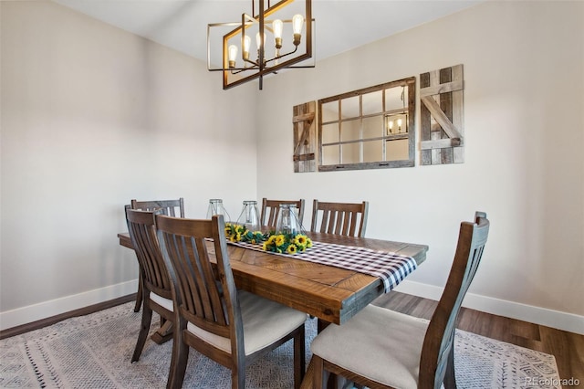 dining space with a notable chandelier, baseboards, and wood finished floors