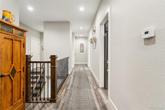 corridor featuring recessed lighting, an upstairs landing, wood finished floors, and baseboards