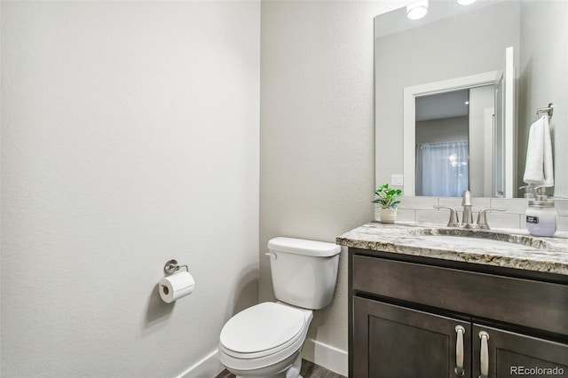 bathroom featuring toilet, vanity, and baseboards