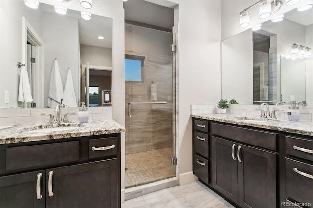 bathroom featuring a shower stall, two vanities, and a sink