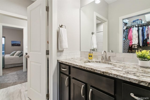 full bathroom with vanity and a walk in closet