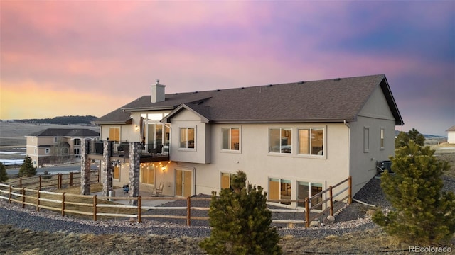 view of front facade with fence, central AC, a chimney, stucco siding, and a patio area