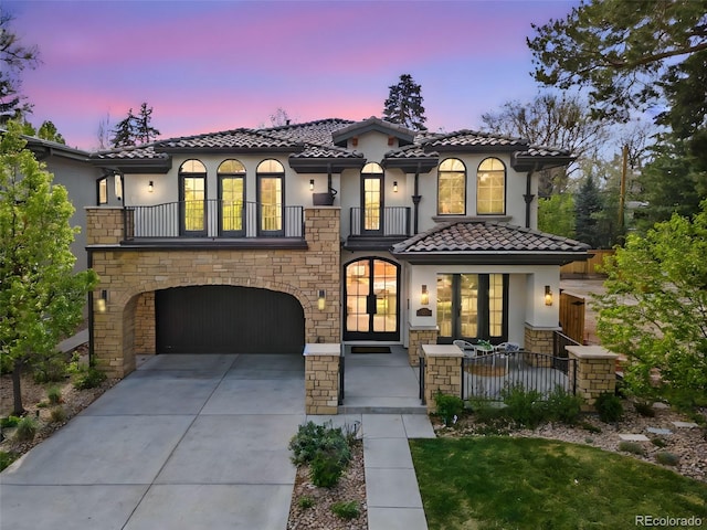 mediterranean / spanish-style home with a balcony, stucco siding, driveway, and a tile roof